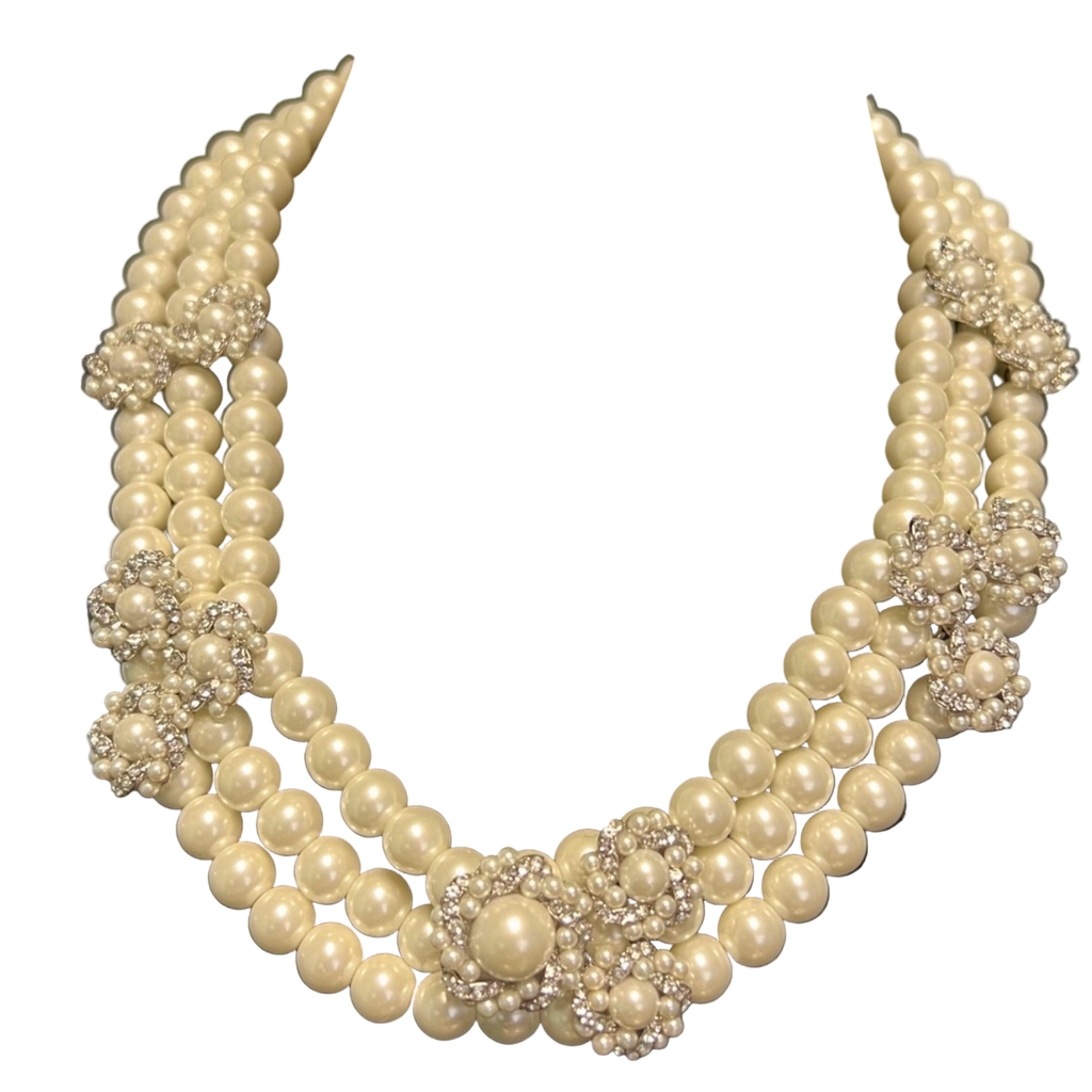 Pearl necklace with silver floral accents on a black velvet stand
