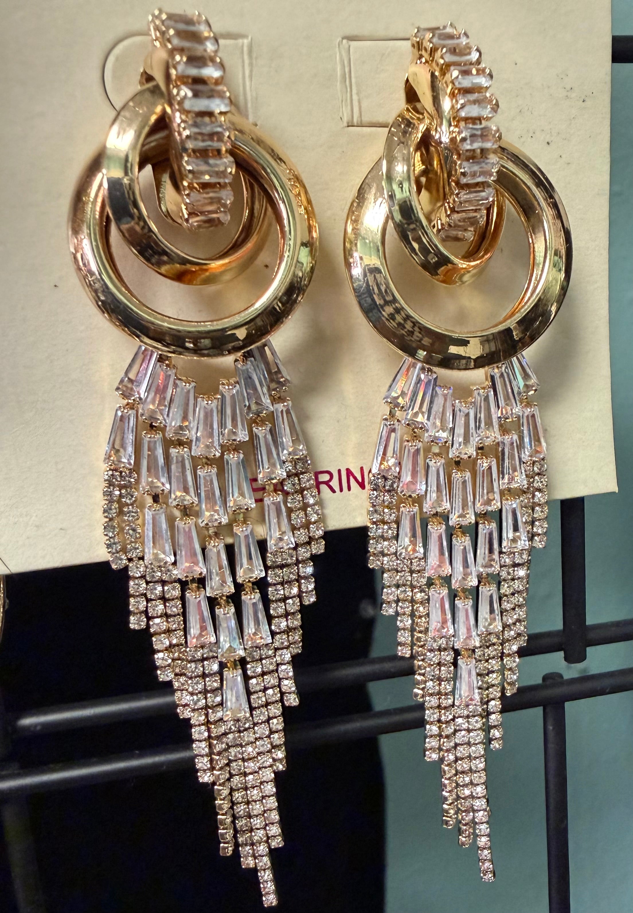 Gold hoop earrings with crystal fringe on a display card.