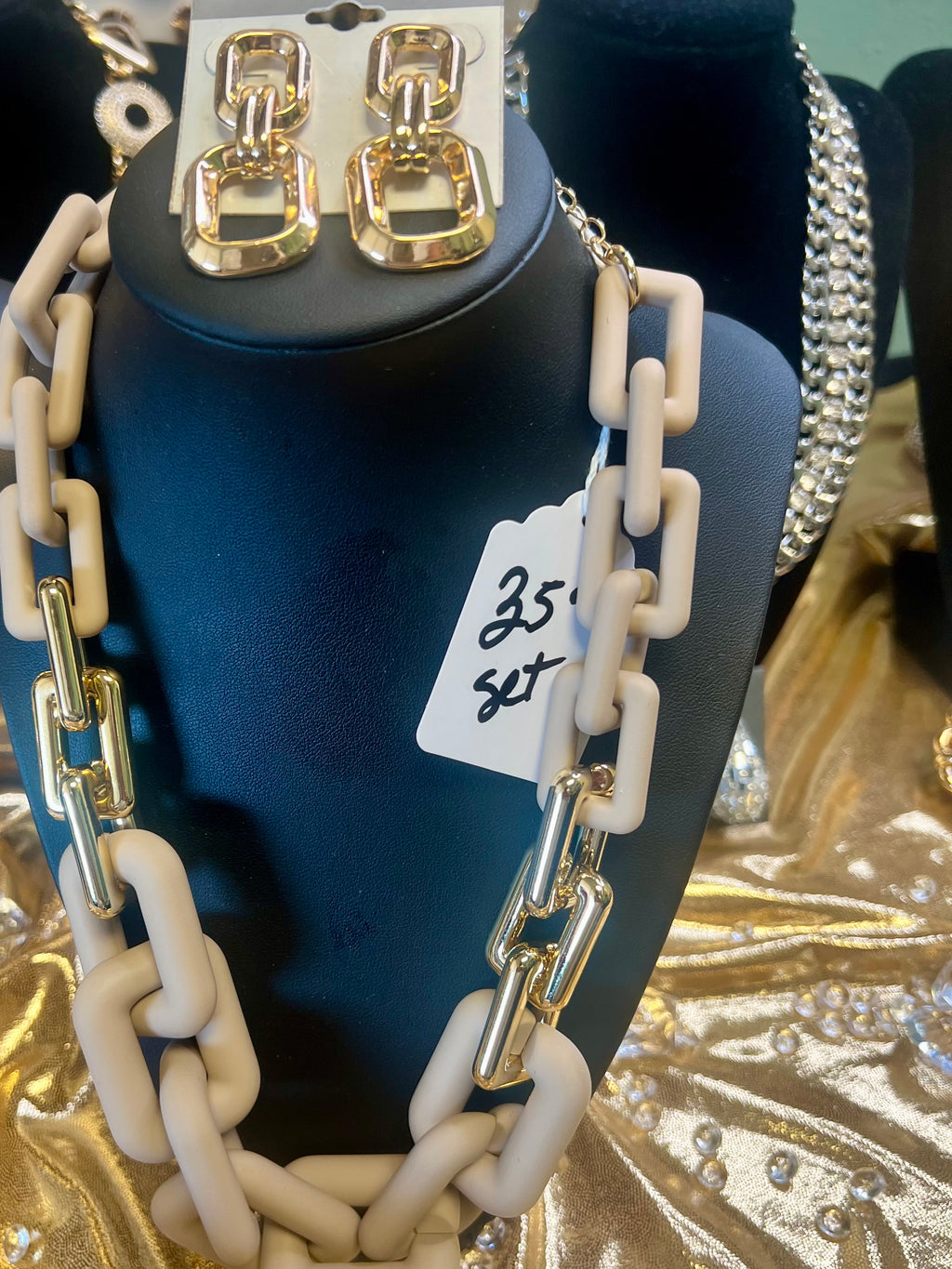 Necklace with gold and beige chain design on a blue mannequin with a price tag.