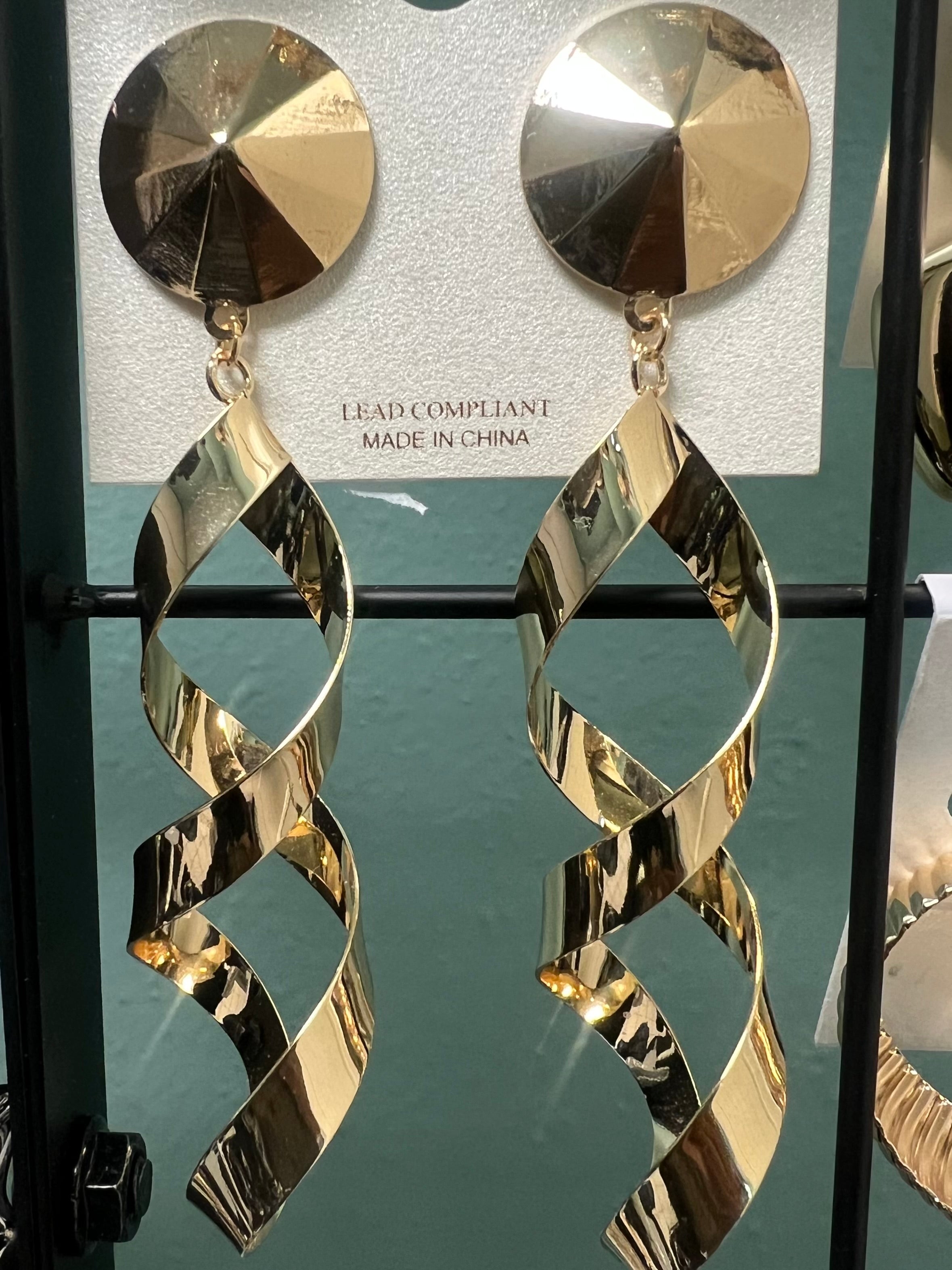 Gold earrings on a display card with a green background