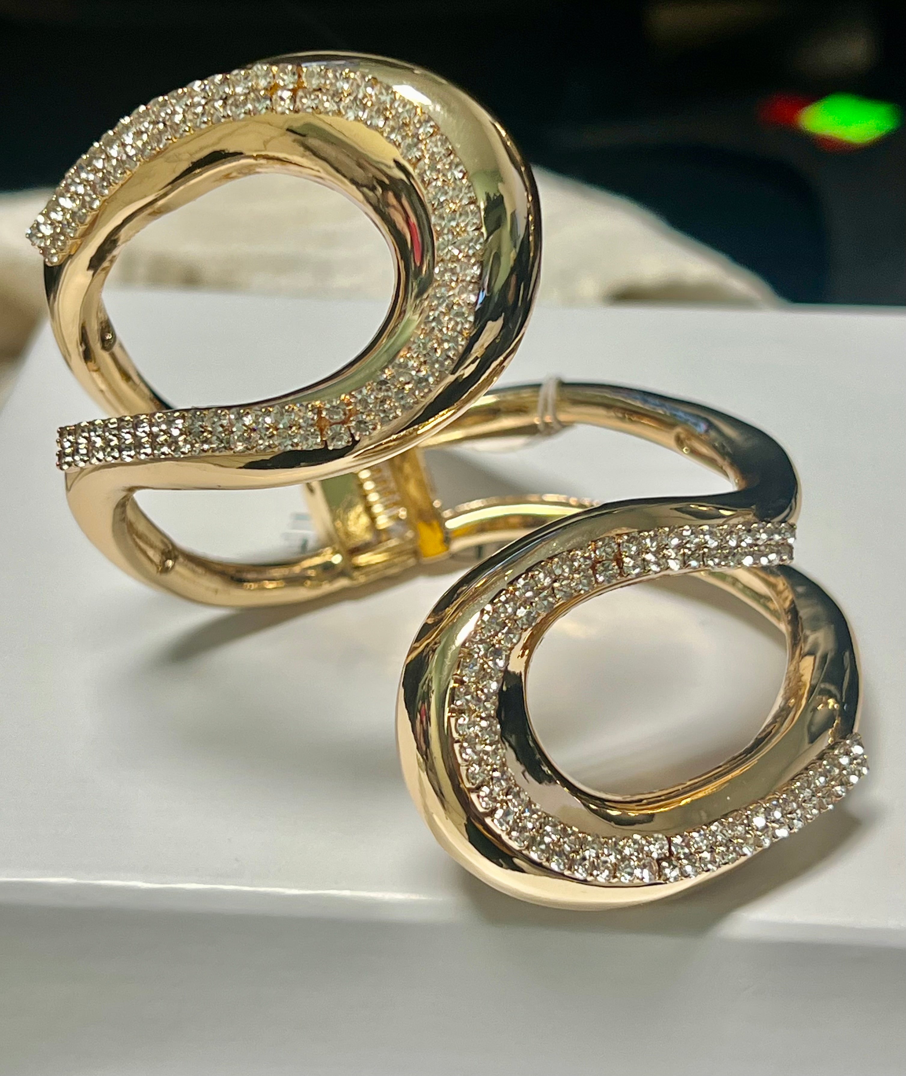 Gold hoop earrings with diamond-like stones on a white surface
