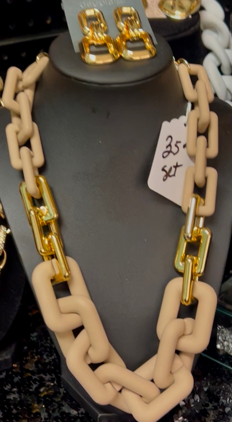 Necklace with gold chain on a mannequin bust with earrings above and a price tag below.
