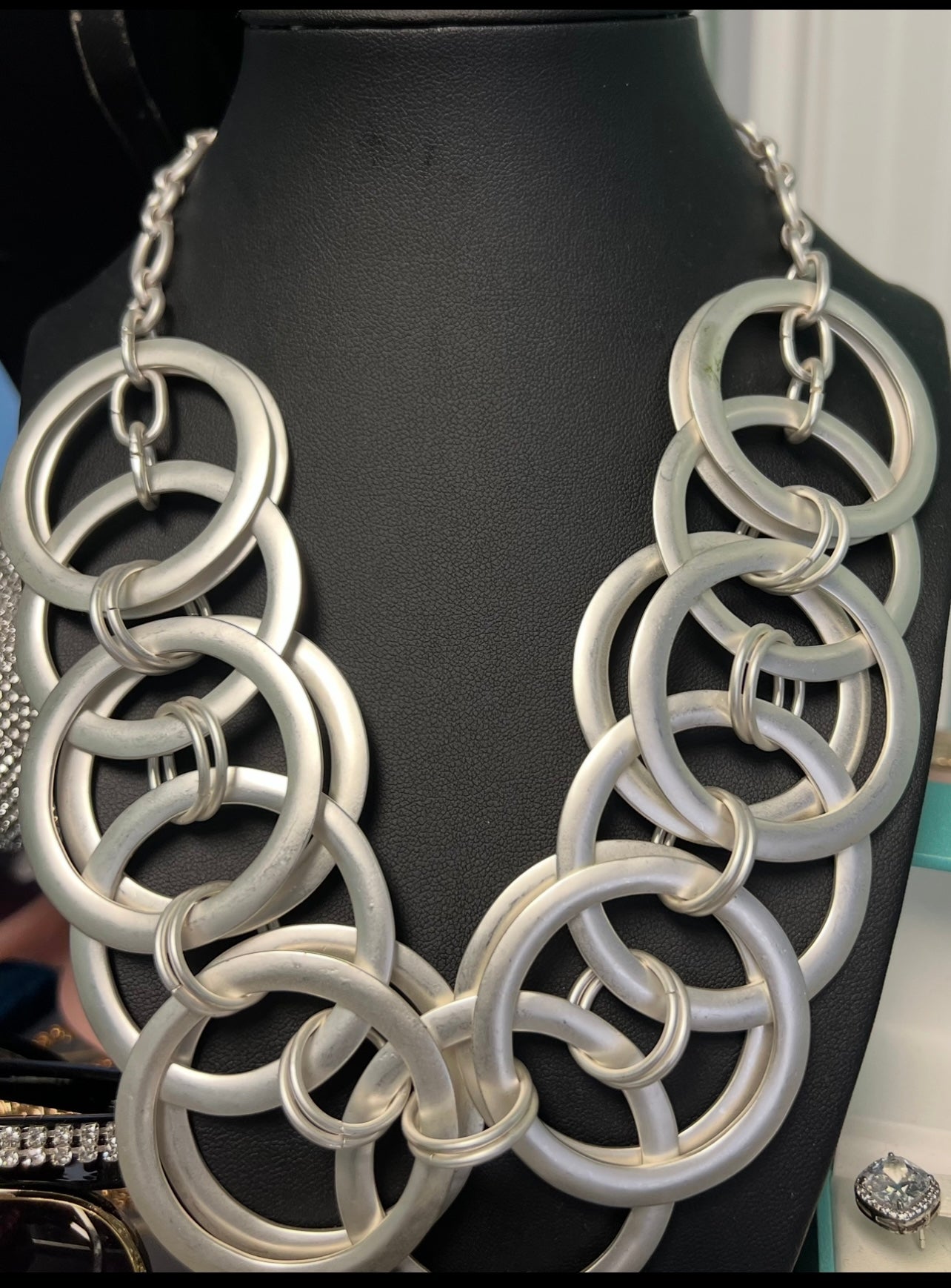 Silver chain necklace on a mannequin with a black background