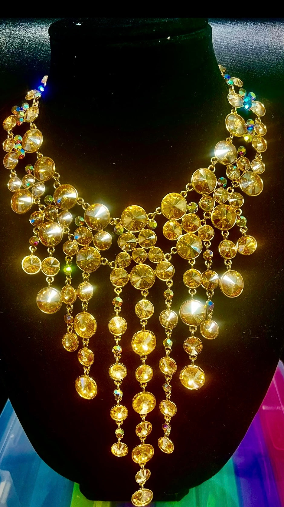 Gold necklace on a black mannequin against a colorful background